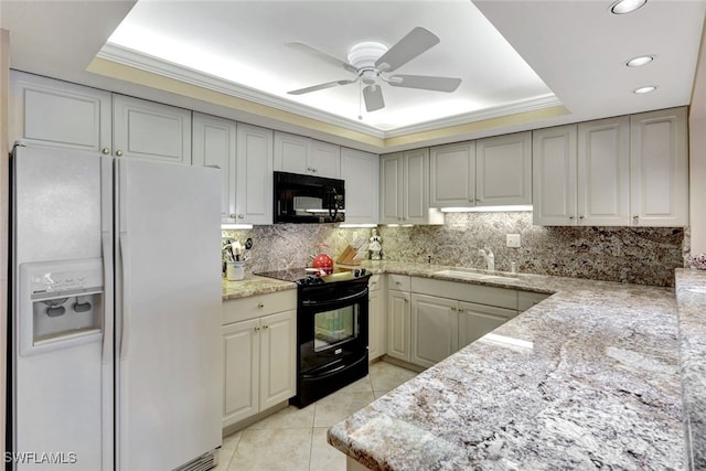 kitchen featuring black appliances, light tile patterned floors, sink, and a tray ceiling