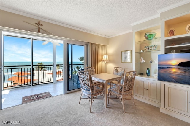 dining space with ceiling fan, crown molding, light colored carpet, a textured ceiling, and a water view