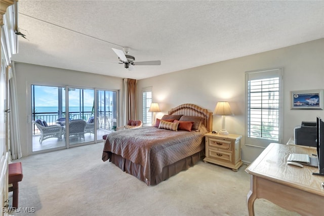 carpeted bedroom with a textured ceiling, access to outside, and multiple windows