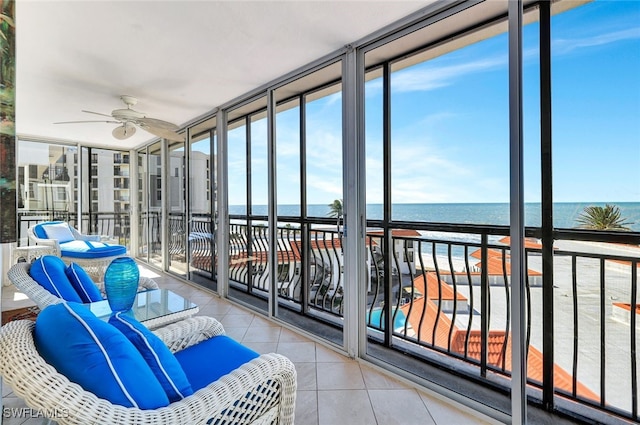 sunroom / solarium with ceiling fan and a water view