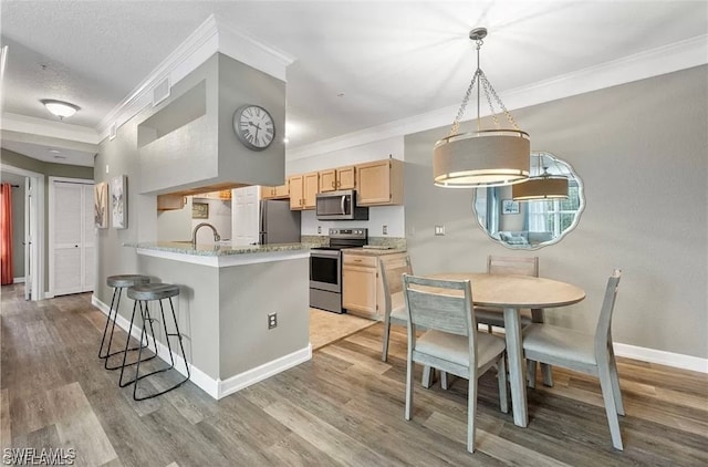 kitchen featuring appliances with stainless steel finishes, light wood-type flooring, ornamental molding, and light brown cabinetry