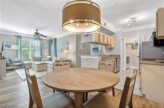 dining room with light wood-type flooring, a textured ceiling, ceiling fan, crown molding, and sink