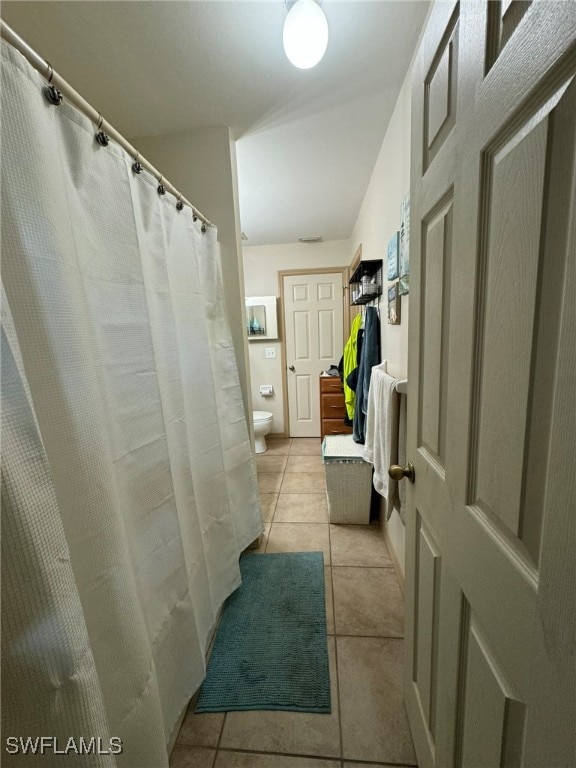 bathroom featuring tile patterned flooring, toilet, and walk in shower