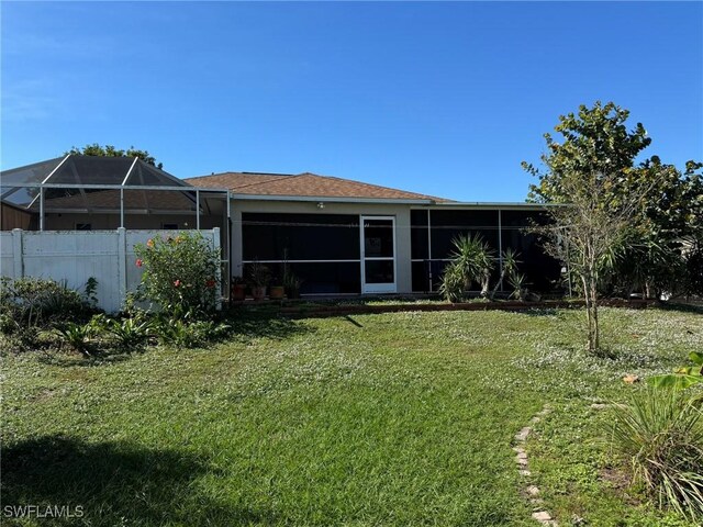 back of property with a lawn and glass enclosure