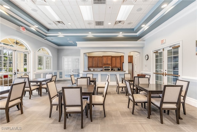 dining space with a raised ceiling, crown molding, and french doors