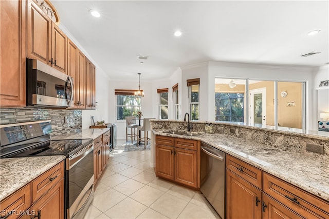 kitchen featuring pendant lighting, crown molding, sink, appliances with stainless steel finishes, and light stone counters