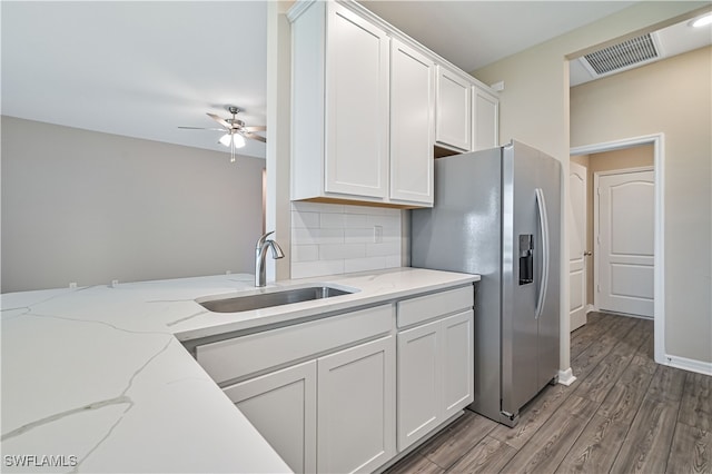 kitchen with white cabinetry, sink, light stone countertops, and hardwood / wood-style flooring