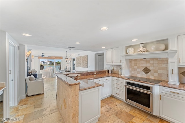 kitchen featuring pendant lighting, white cabinets, oven, black electric stovetop, and kitchen peninsula