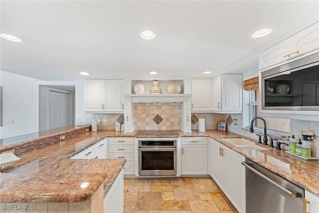 kitchen featuring kitchen peninsula, white cabinetry, light stone counters, and appliances with stainless steel finishes