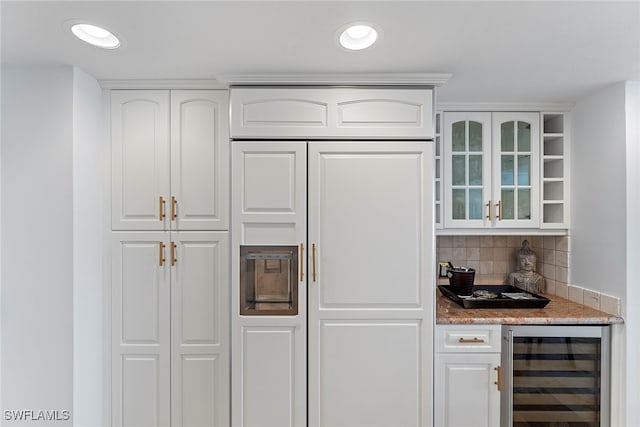 kitchen with white cabinets, decorative backsplash, light stone countertops, and wine cooler