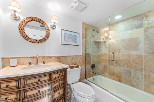 full bathroom featuring vanity, toilet, tile walls, and enclosed tub / shower combo