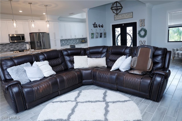 living room with crown molding, a chandelier, and light wood-type flooring