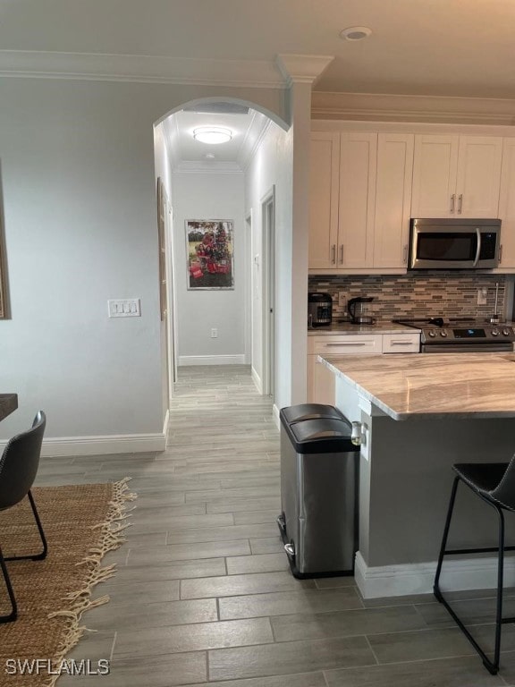 kitchen featuring white cabinets, backsplash, stainless steel appliances, and light hardwood / wood-style flooring