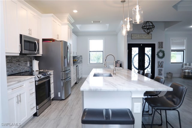 kitchen with appliances with stainless steel finishes, white cabinetry, a breakfast bar area, and sink