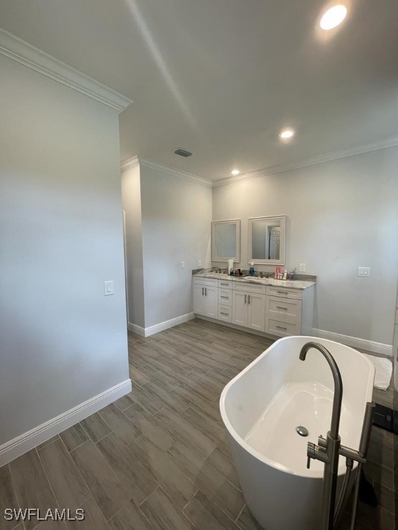 bathroom with hardwood / wood-style flooring, vanity, a bath, and ornamental molding