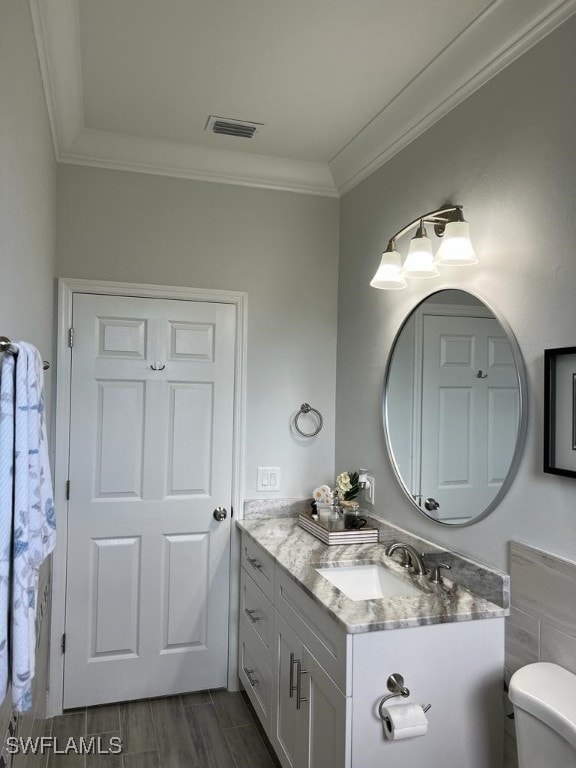 bathroom with hardwood / wood-style floors, vanity, ornamental molding, and toilet