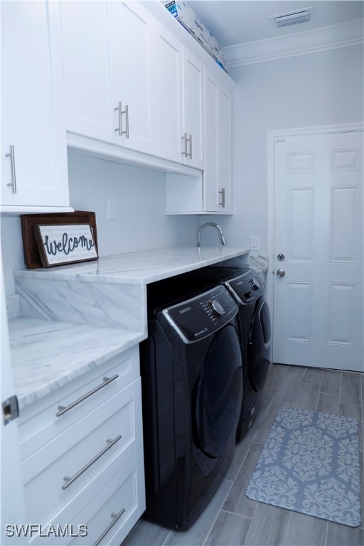 clothes washing area with light hardwood / wood-style floors, cabinets, independent washer and dryer, and ornamental molding