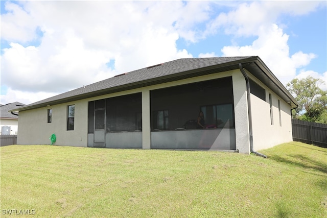 rear view of house featuring a yard and a sunroom