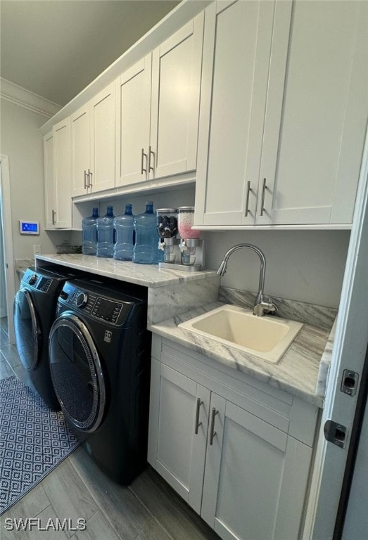 laundry room with cabinets, light wood-type flooring, crown molding, sink, and washing machine and dryer