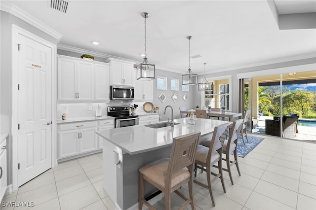 kitchen featuring sink, an island with sink, a breakfast bar, white cabinets, and appliances with stainless steel finishes