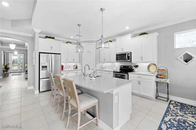 kitchen with pendant lighting, sink, appliances with stainless steel finishes, white cabinets, and a kitchen bar