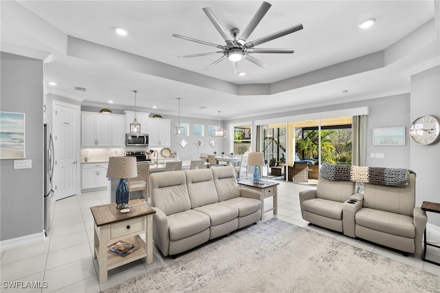 tiled living room with sink, ornamental molding, a raised ceiling, and ceiling fan