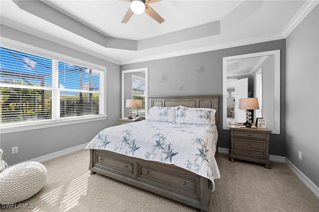 bedroom featuring ceiling fan, ornamental molding, a tray ceiling, and light carpet