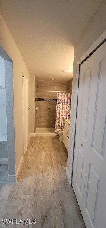 bathroom featuring toilet, hardwood / wood-style floors, and a shower with shower curtain