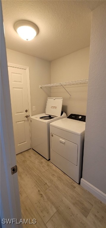 laundry room featuring washer and clothes dryer, light hardwood / wood-style floors, and a textured ceiling