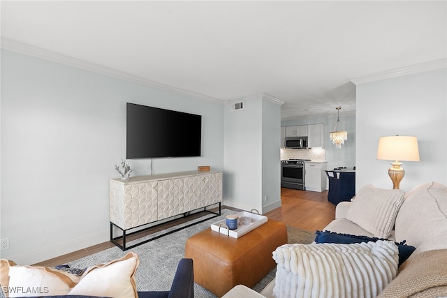 living room with light wood-type flooring and ornamental molding