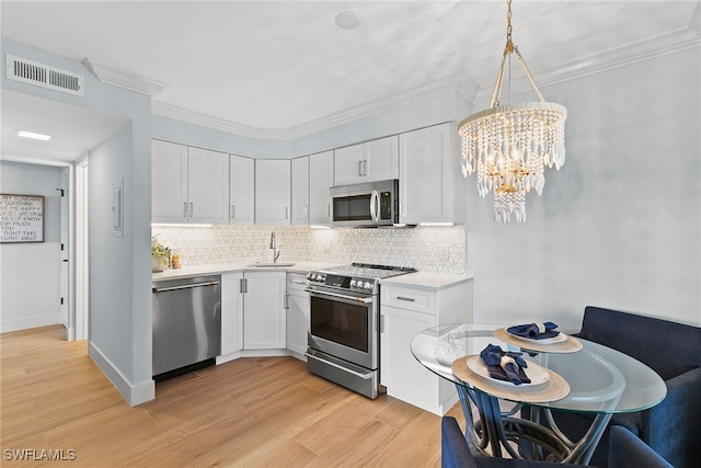 kitchen with decorative light fixtures, white cabinetry, sink, and appliances with stainless steel finishes