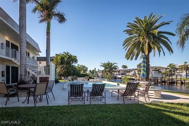 view of pool with a yard, a water view, and a patio