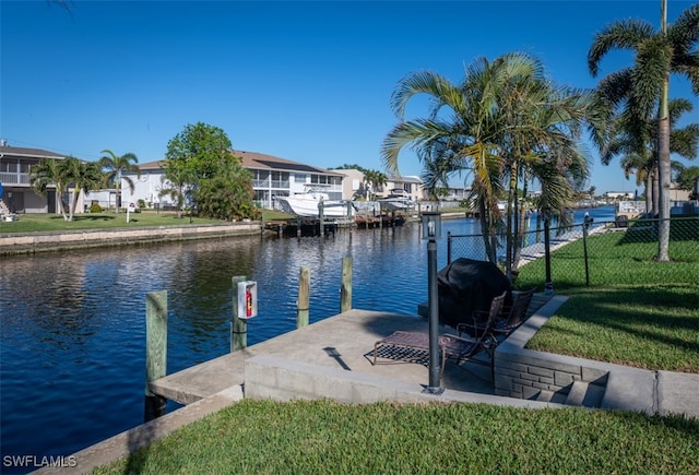 view of dock with a lawn and a water view