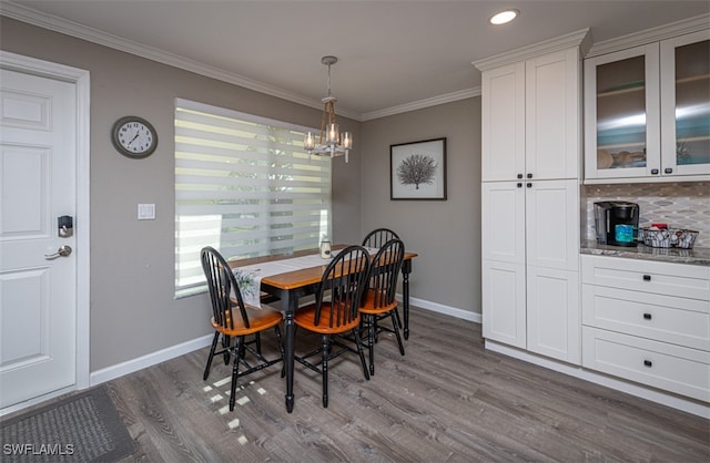 dining room with wood-type flooring, crown molding, and a notable chandelier