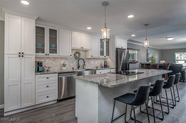 kitchen with appliances with stainless steel finishes, dark hardwood / wood-style flooring, decorative light fixtures, white cabinetry, and a kitchen island