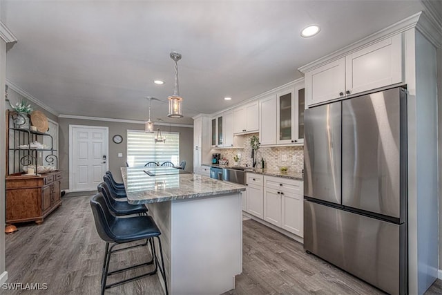 843 SE 46th Ln Unit 1, Cape Coral, FL 33904 - kitchen with appliances with stainless steel finishes, white cabinets, dark wood-style flooring, ornamental molding, and a kitchen island