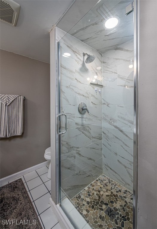 bathroom featuring tile patterned floors, toilet, and a shower with door