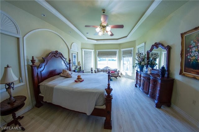 bedroom featuring ceiling fan, light hardwood / wood-style floors, a raised ceiling, and ornamental molding