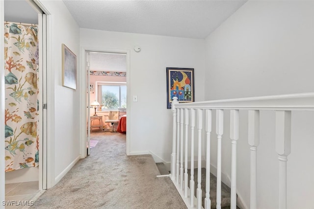 hall with carpet flooring and a textured ceiling