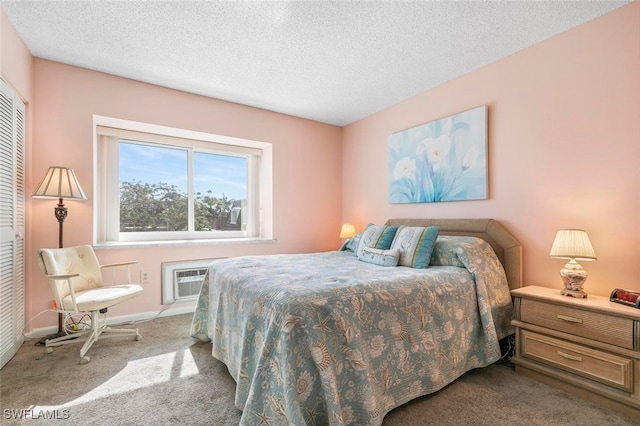 carpeted bedroom featuring a textured ceiling, a wall unit AC, and a closet