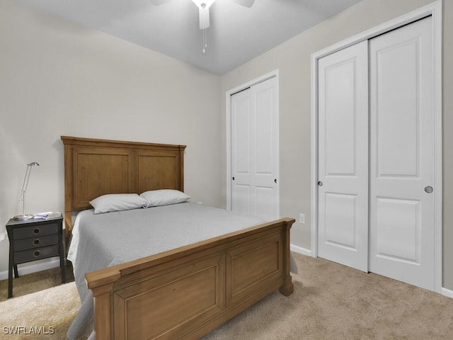 carpeted bedroom featuring ceiling fan and two closets