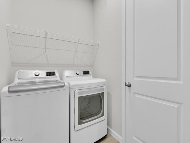 washroom with separate washer and dryer and light wood-type flooring