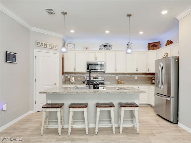 kitchen featuring a kitchen island with sink, light stone countertops, white cabinetry, and stainless steel appliances