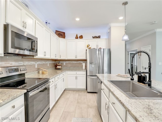 kitchen featuring hanging light fixtures, appliances with stainless steel finishes, sink, white cabinets, and decorative backsplash