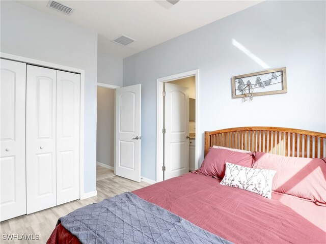 bedroom with a closet, visible vents, baseboards, and wood finished floors