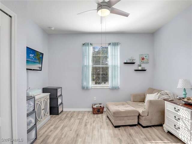 living area with light wood-type flooring, baseboards, and a ceiling fan