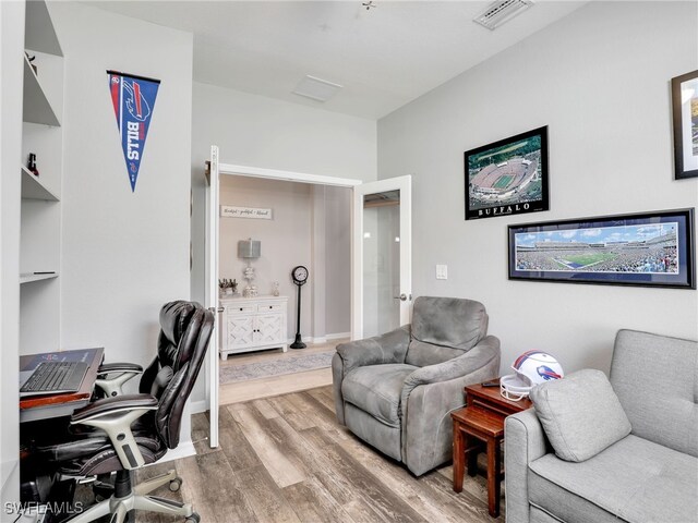 home office featuring light hardwood / wood-style floors, built in features, and french doors