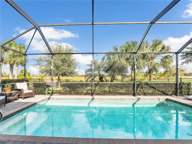 view of pool with glass enclosure and a patio