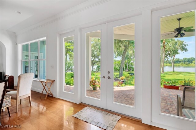 entryway with french doors, ceiling fan, crown molding, a water view, and hardwood / wood-style floors