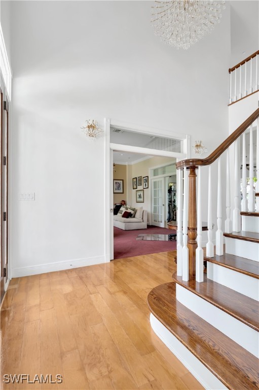 entrance foyer featuring hardwood / wood-style floors, an inviting chandelier, french doors, and a high ceiling